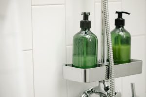 Two containers of soap or shampoo sit on a tray in a shower.
