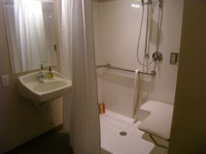 An accessible walk-in shower with bars and a shower seat.